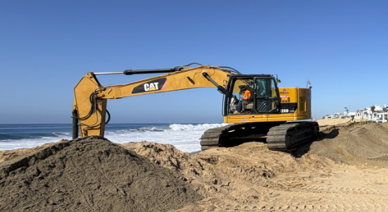 Bulldozers move sand along the coast of Newport Beach